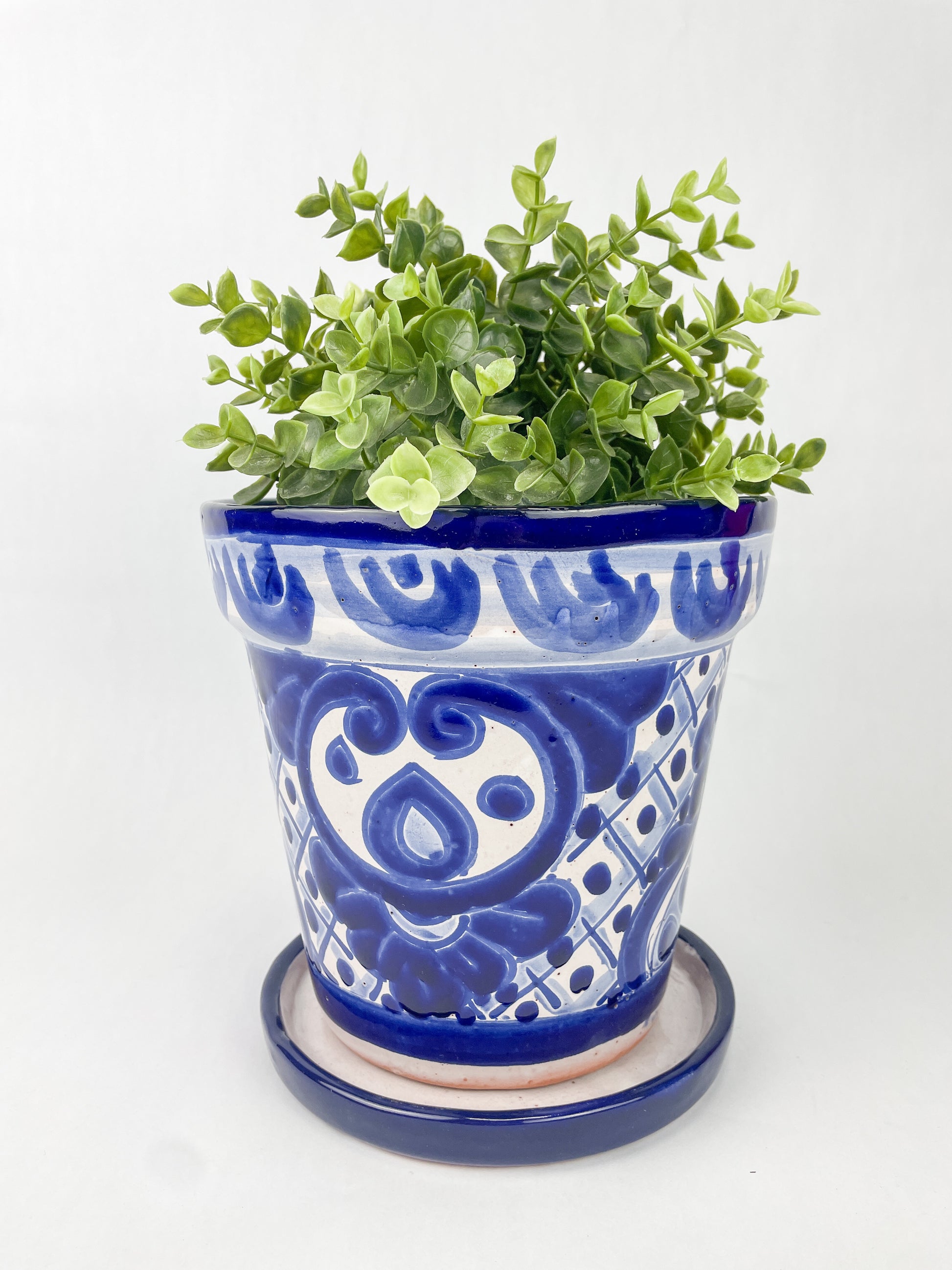 Hand-painted Talavera flower pot featuring vibrant floral design, part of authentic Mexican pottery collection. Talavera planters showcase traditional folk art on rustic furniture. Talavera tile adorns walls alongside Talavera animals in rich colors
