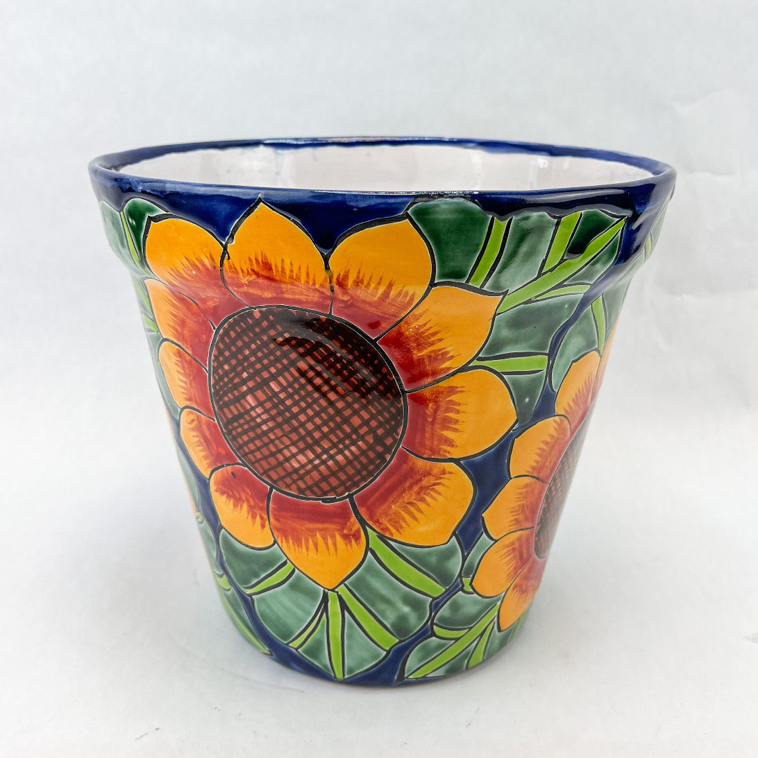 Hand-painted Talavera flower pot featuring vibrant floral design, part of authentic Mexican pottery collection. Talavera planters showcase traditional folk art on rustic furniture. Talavera tile adorns walls alongside Talavera animals in rich colors