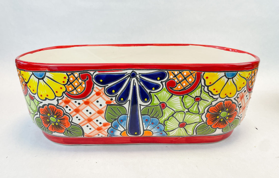 Hand-painted Talavera flower pot featuring vibrant floral design, part of authentic Mexican pottery collection. Talavera planters showcase traditional folk art on rustic furniture. Talavera tile adorns walls alongside Talavera animals in rich colors