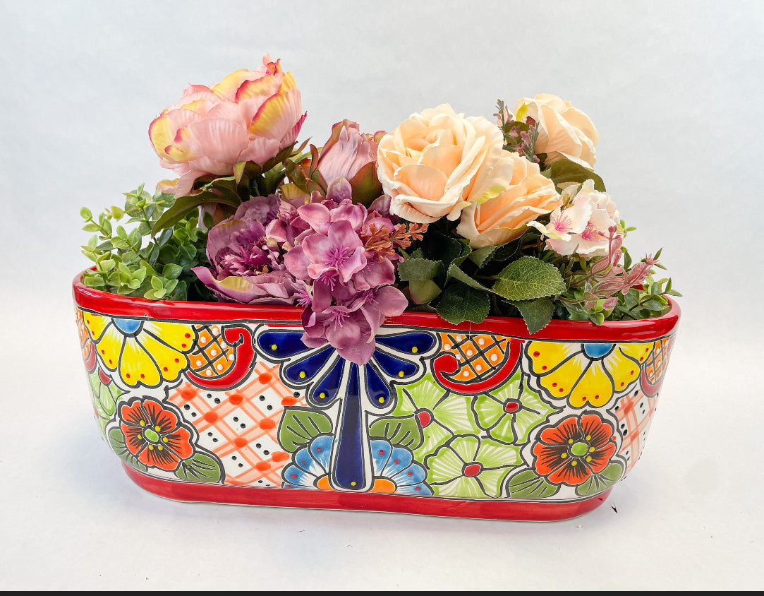 Hand-painted Talavera flower pot featuring vibrant floral design, part of authentic Mexican pottery collection. Talavera planters showcase traditional folk art on rustic furniture. Talavera tile adorns walls alongside Talavera animals in rich colors