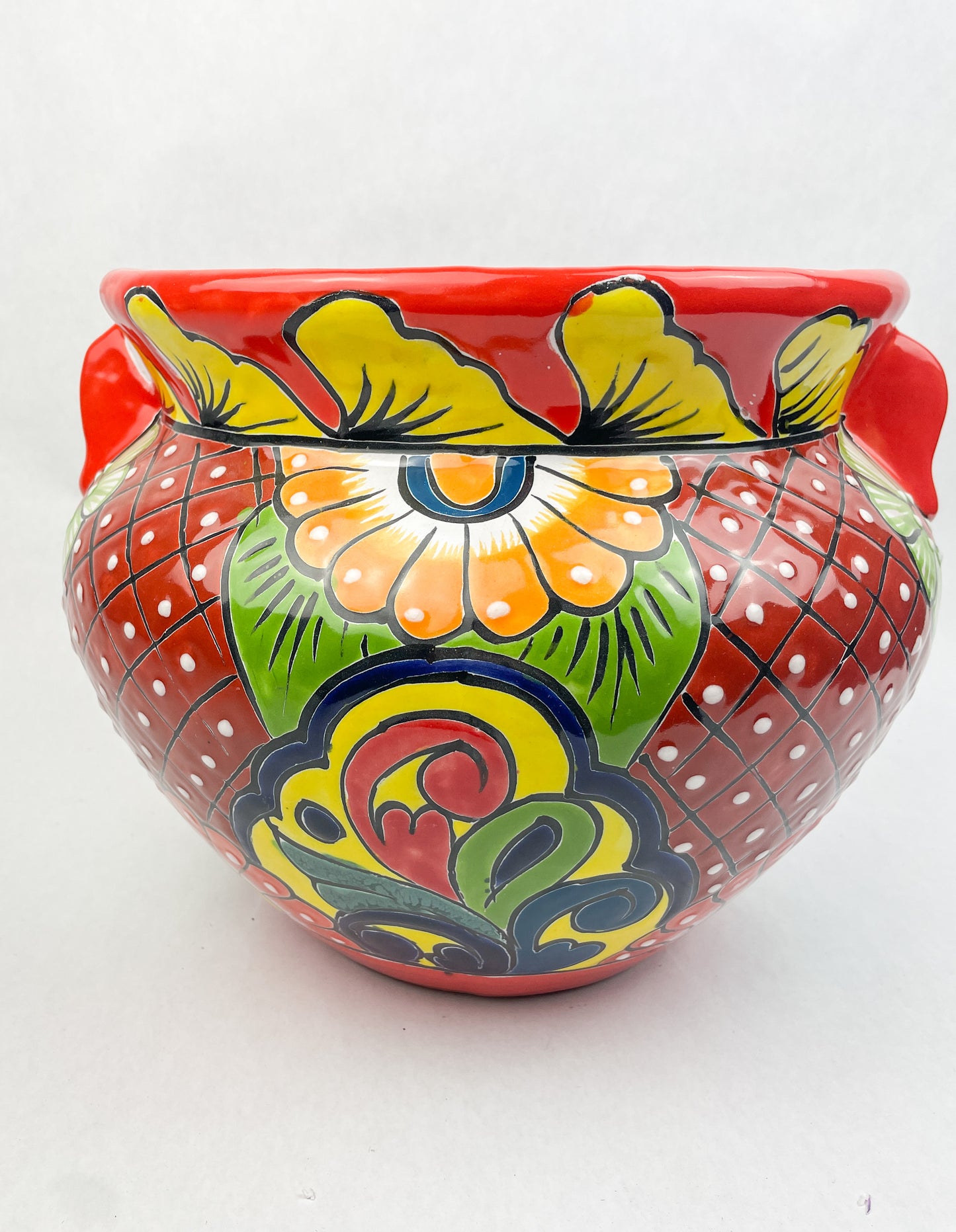 Hand-painted Talavera flower pot featuring vibrant floral design, part of authentic Mexican pottery collection. Talavera planters showcase traditional folk art on rustic furniture. Talavera tile adorns walls alongside Talavera animals in rich colors