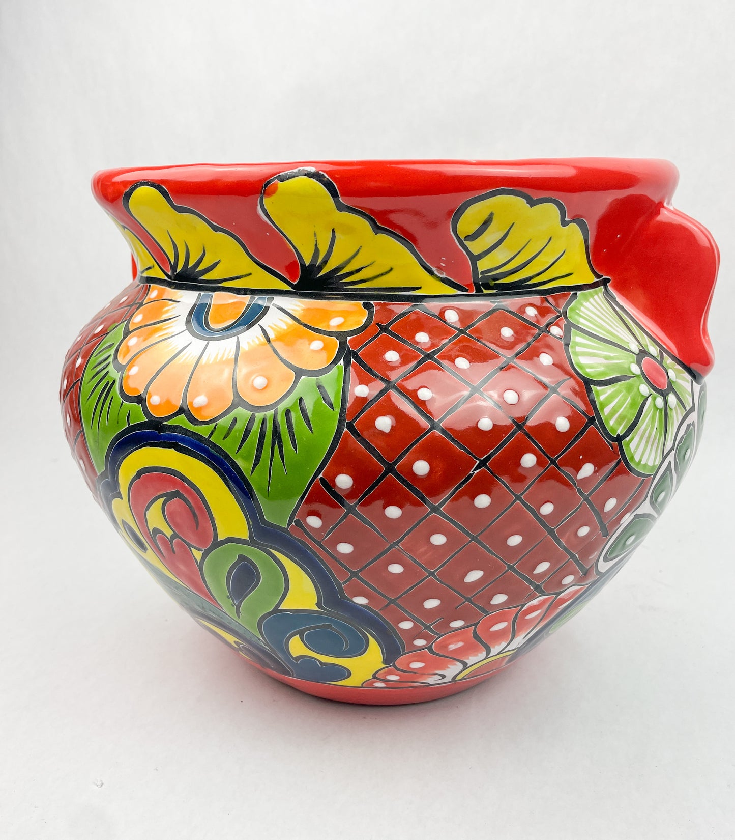 Hand-painted Talavera flower pot featuring vibrant floral design, part of authentic Mexican pottery collection. Talavera planters showcase traditional folk art on rustic furniture. Talavera tile adorns walls alongside Talavera animals in rich colors
