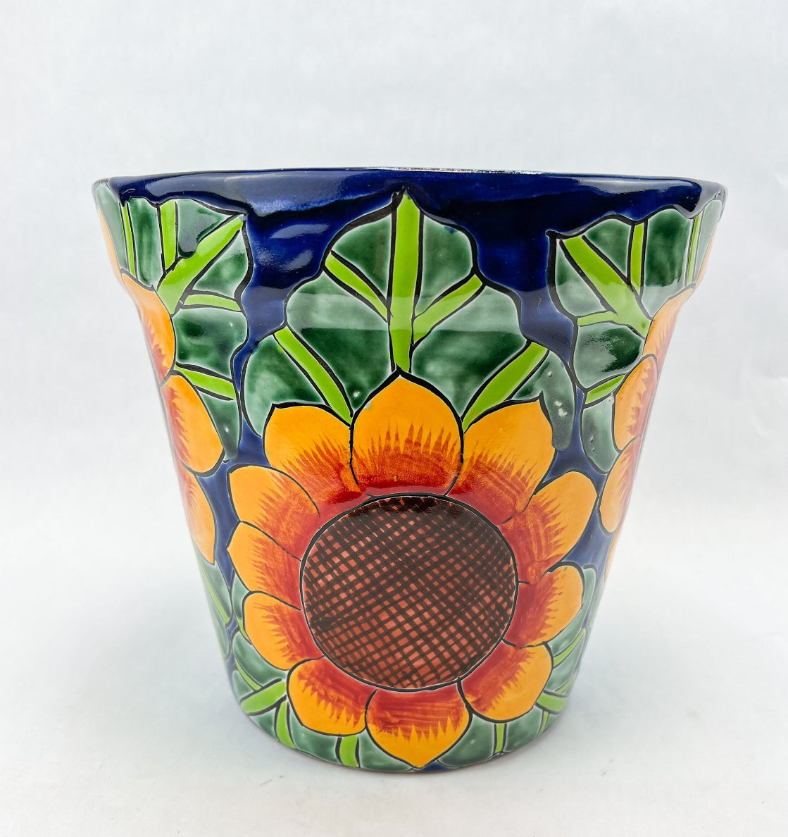 Hand-painted Talavera flower pot featuring vibrant floral design, part of authentic Mexican pottery collection. Talavera planters showcase traditional folk art on rustic furniture. Talavera tile adorns walls alongside Talavera animals in rich colors