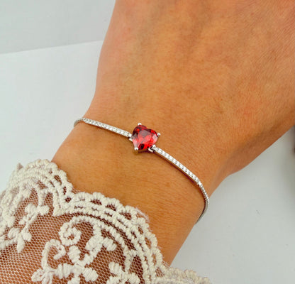 Woman wearing a Silver Sterling 925 adjustable bracelet featuring a red CZ heart charm and delicate pavé accents on the wrist.